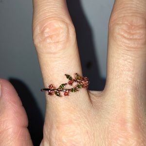 Rose Gold ring with green and red jewels.